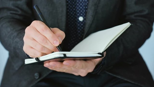 Business guy in black suit writing in day planner. Generating creative ideas outlining ambitious project successful strategy.