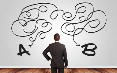 Businessman looking for connection between two things while standing in front of a wall
