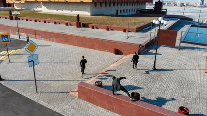 Three young men overcoming obstacles and running on the streets. Aerial view