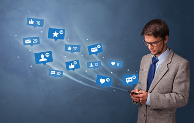 Young person using phone with flying social media icons around
