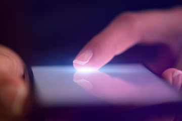 Finger touching phone with dark background with copyspace
