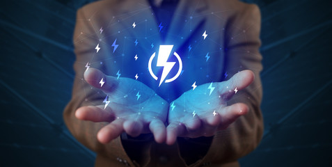 Hand in suit holding lightning bolt on his hand, green environment concept
