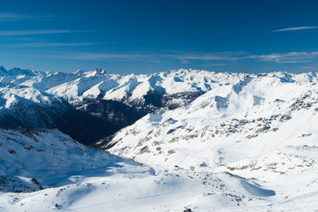 Fototapeta na wymiar Panoramic view down snow covered valley in alpine mountain range