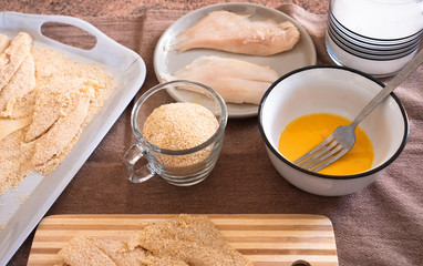 Breaded fish filets with eggs. Freshness on the table with wooden chopping board and salt