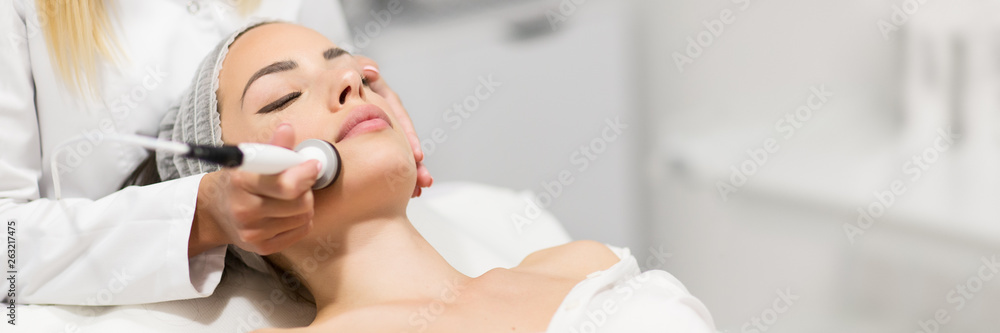 Wall mural beautiful woman in professional beauty salon during photo rejuvenation procedure