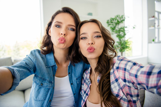 Close up photo beautiful she her ladies buddies meeting gathering make take selfies send air kiss coquette wear casual jeans denim checkered plaid shirts apartments sit comfy divan couch room indoors