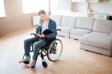 Young student with inclusion and disability. Looking on opened book and talking on phone. Studying...