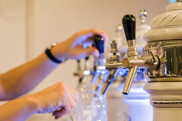 Beer tap in row with barman pouring fresh beer into the glass at restaurant or pub. 