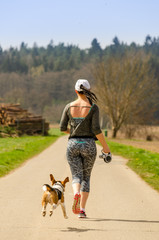 Girl running with Beagle dog outdoors in nature.