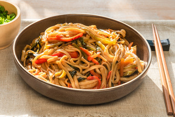 Traditional Chinese vegetarian noodles lo mein on a plate with chopsticks, top view