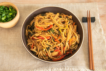 Traditional Chinese vegetarian noodles lo mein on a plate with chopsticks, top view