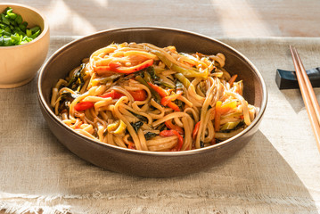 Traditional Chinese vegetarian noodles lo mein on a plate with chopsticks, top view