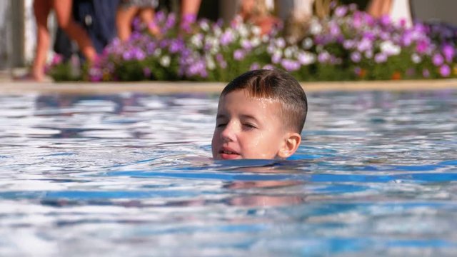 Happy Boy Swims in a Pool with Blue Water at the Hotel. Slow Motion