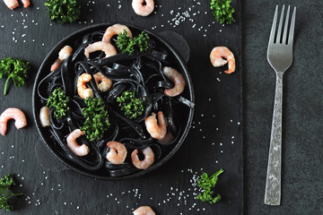 Black noodles with shrimp and greens. Food trends. Black food.