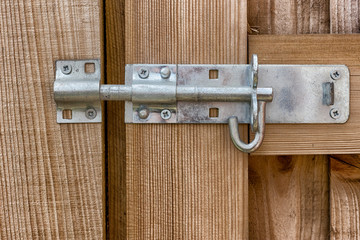 A steel bolt latch on a wooden gat close up