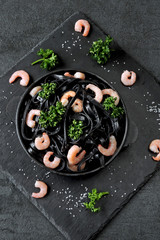 Black noodles with shrimp and greens. Food trends. Black food.