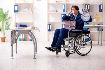 Young male employee in wheelchair working in the office 