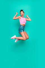 Fototapeta na wymiar Vertical full length side profile body size photo beautiful she her funny yelling trendy hairdo jump high lucky lottery wear casual pink tank-top jeans denim shorts isolated teal turquoise background