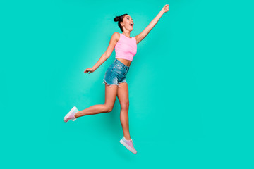 Full length side profile body size photo beautiful she her jump high trendy stylish hairdo pretend umbrella flight wear casual pink tank-top jeans denim shorts isolated teal turquoise background