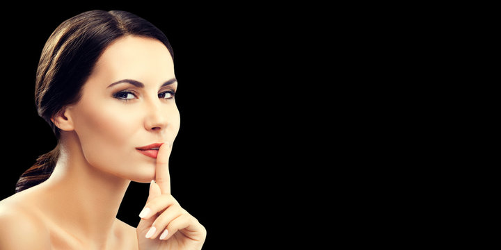 Woman keeping finger on her lips, isolared on black