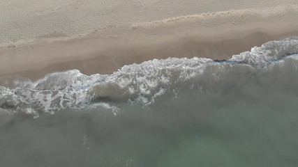 Aerial view of waves crashing on the shore with foam and undertow - Powered by Adobe