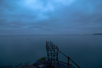 Marine landscape in the Blue hour with a metal construction that once was a bridge. From the shore of the Black Sea in Pomorie, Bulgaria.