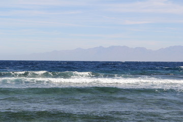 Fototapeta na wymiar Sea with waves and mountains on the horizon