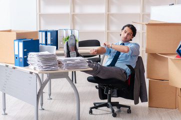 Young man employee with boxes in the office 