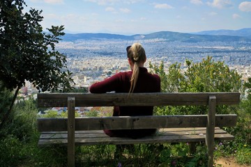 girl sitting on a bench on a high mountain overlooking the big city