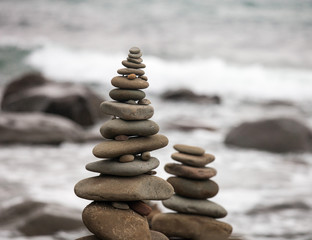 Pyramids from pebble on the sea coast. Little cairns on the background of the sea. Landscape for meditation.