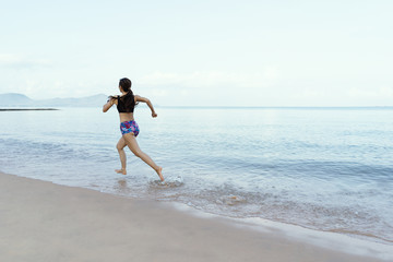 Middle-aged women who is running by the sea with blue skies and clean white sand. good health and happiness concept.