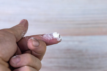 cocaine, heroin: a powdered narcotic drug on the tip of a man's finger, on a light background.