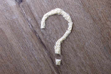 strip of cocaine in the form of a question mark, on a wooden table, toning.