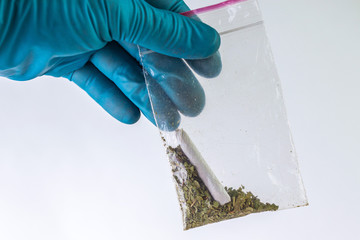 weed and ready-made narcotic cigarette in a bag in the hand of a police expert