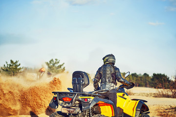 Teen riding ATV in sand dunes making a turn in the sand