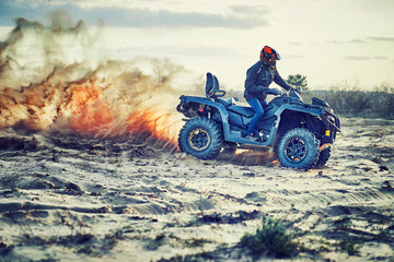 Teen riding ATV in sand dunes making a turn in the sand