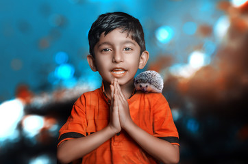 Adorable cute Indian boy child welcoming with hedgehog on shoulder bokeh background