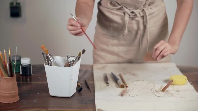 Woman artist is putting her instrument in coaster on working table, close-up