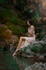 Beautiful girl posing in river. Fairytale story. Natural pool surrounded by green tree's leafs.