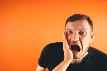 Man getting slapped on orange background.
Unhappy scared man getting slapped standing on orange background