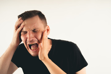 Emotional male getting slapped in face while shouting with closed eyes in fear on white background