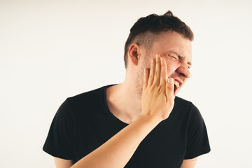 Emotional male getting slapped in face while shouting with closed eyes in fear on white background