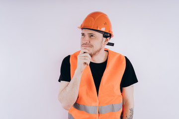 Man in working uniform on white background Portrait of young male in bright orange protective hardhat and vest looking at camera on white background