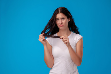 Sad woman is pulling her hair on blue background