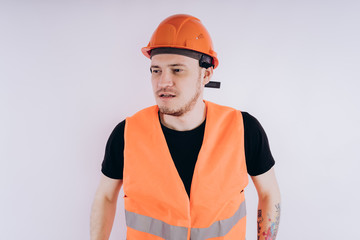 Man in working uniform on white background Portrait of young male in bright orange protective hardhat and vest looking at camera on white background