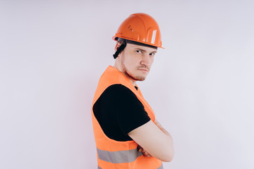 Man in working uniform on white background Portrait of young male in bright orange protective hardhat and vest looking at camera on white background