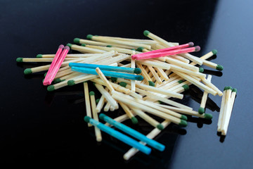 homosexuality concept: several pairs of blue and pink matches in front of a pile of ordinary matches, black background, short focus, limited lighting, toning