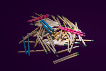 homosexuality concept: several pairs of blue and pink matches in front of a pile of ordinary matches, black background, short focus, limited lighting, toning