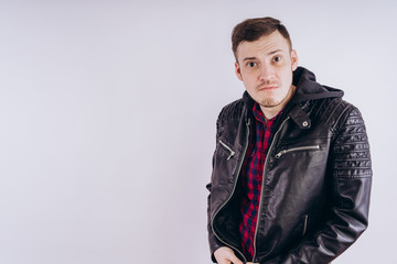 Fototapeta premium Man in trendy jacket on white background. Portrait of young male in leather jacket zipping up and smiling at camera on white background