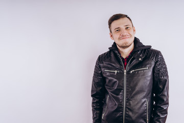 Man in trendy jacket on white background. Portrait of young male in leather jacket zipping up and smiling at camera on white background